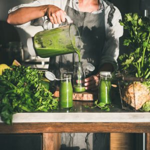 A freshly made green smoothie being poured in a glass.