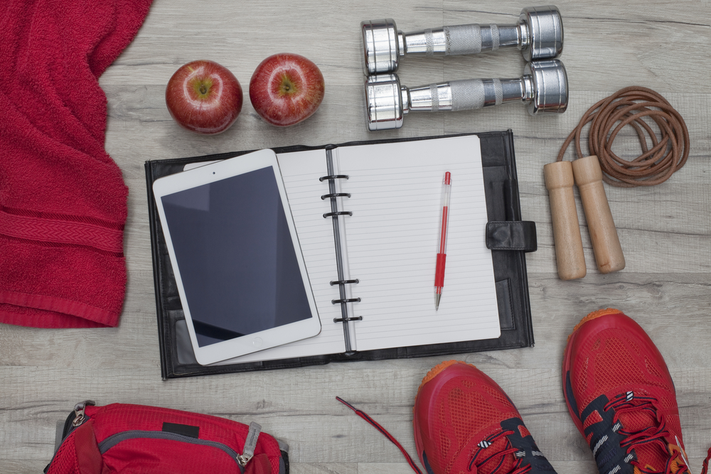 A workout journal, dumbells, jump rope, apples, sneakers and other tools for fulfilling your goals for the new year