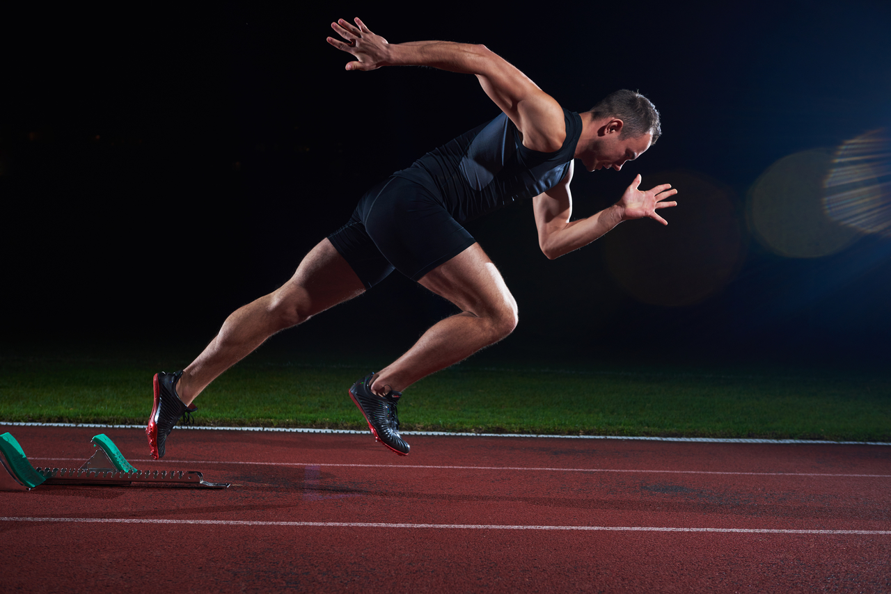 Sprinter leaving the starting block on a race track.