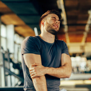 A man holding his arm while grimacing from pain.