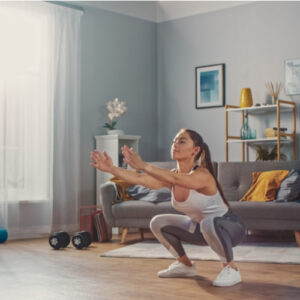 A fit woman doing a squat exercise at home.