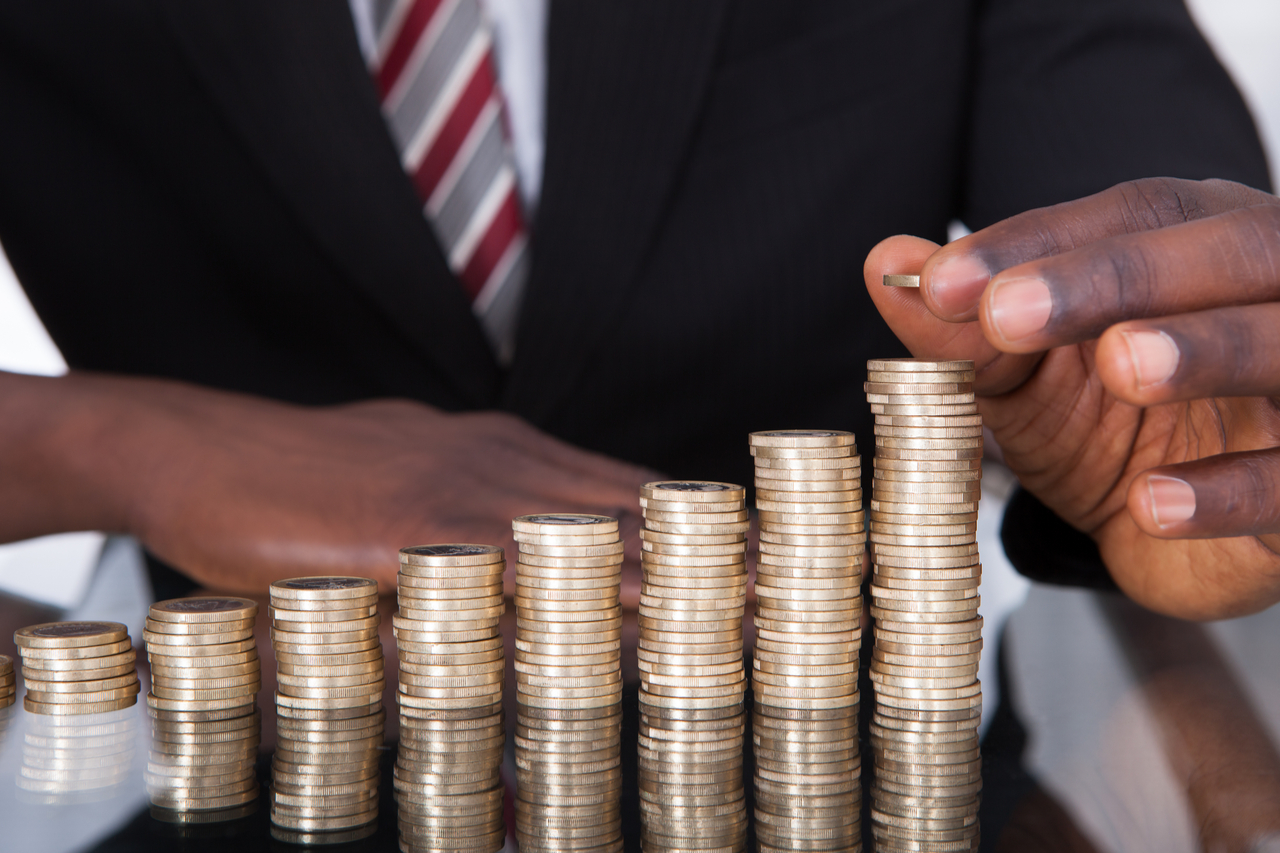 An african american businessman stacking coins on a glass table.