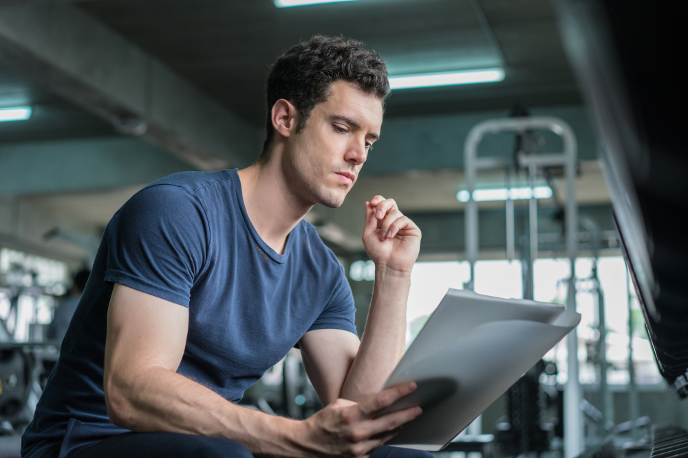  trainer looking at fitness plan on clipboard for working out in the fitness gym.