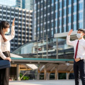 Business man and woman greet and say hello with business colleague and wearing mask standing distance of 1 meter distance protect from COVID-19