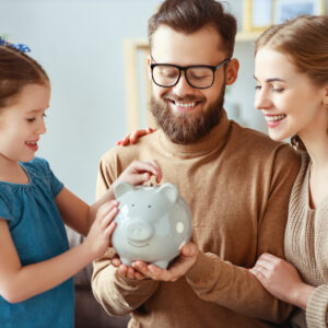 family putting money into a piggy bank