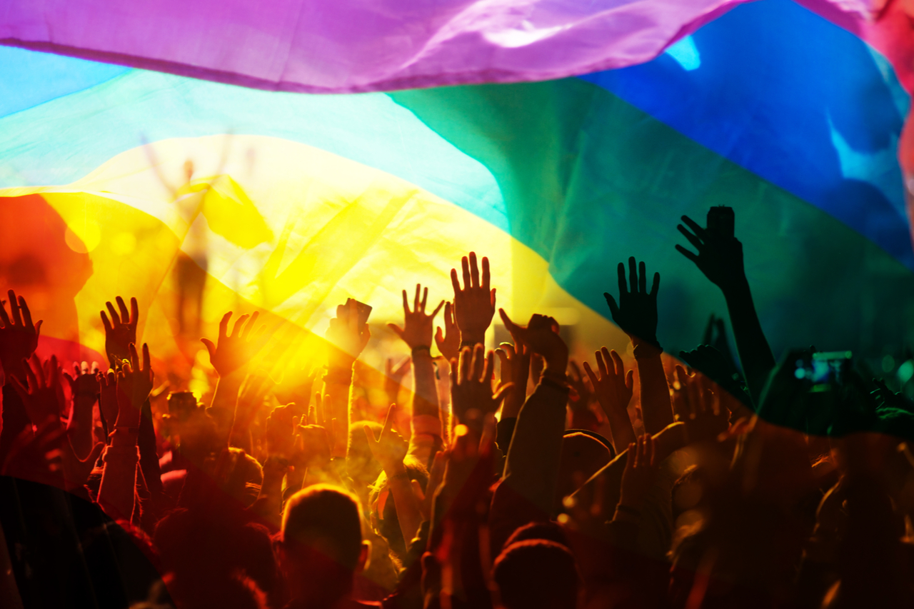 Silhouette of a rainbow flag symbolizing pride with the LGBTQ having a parade.