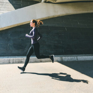 Woman jogging or running, side view with her shadow on the ground.
