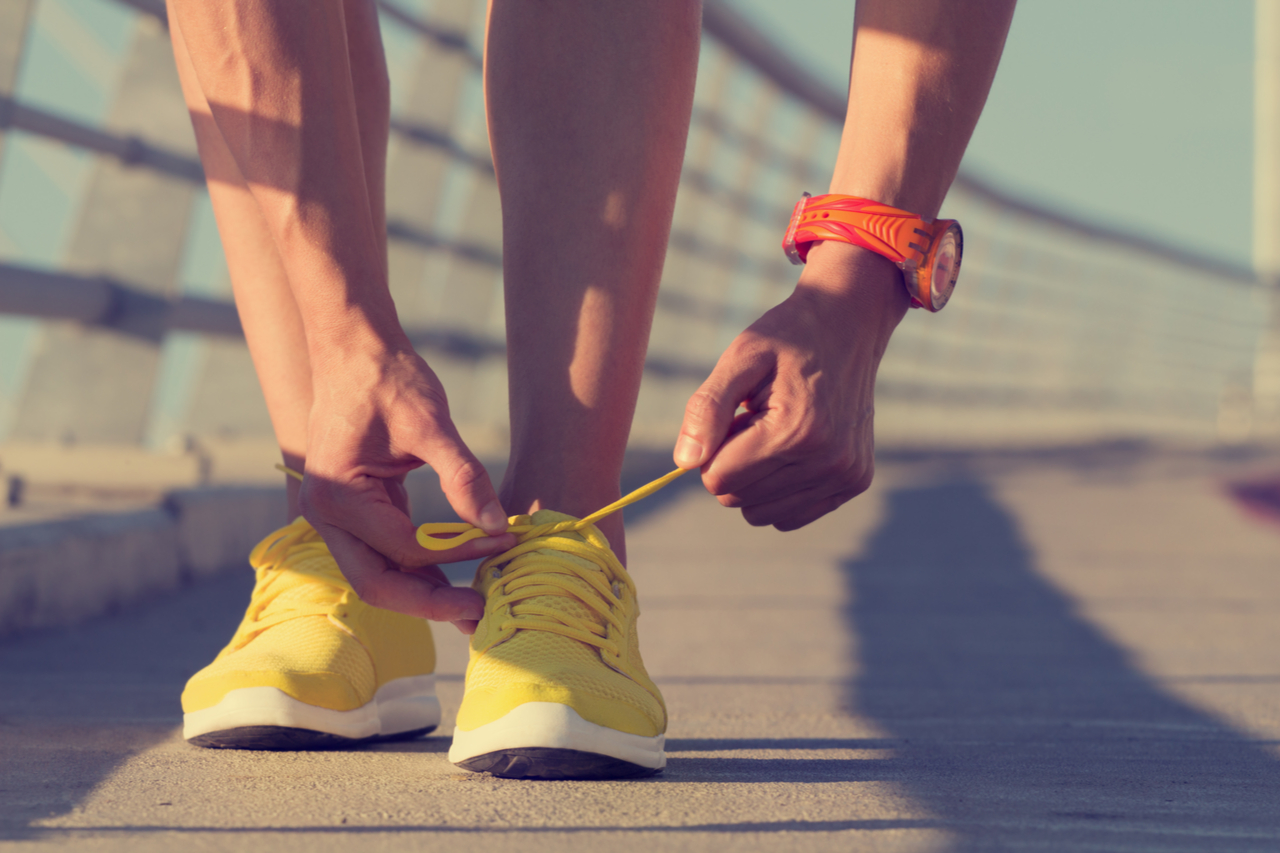 Man tying his shoelaces on before running.