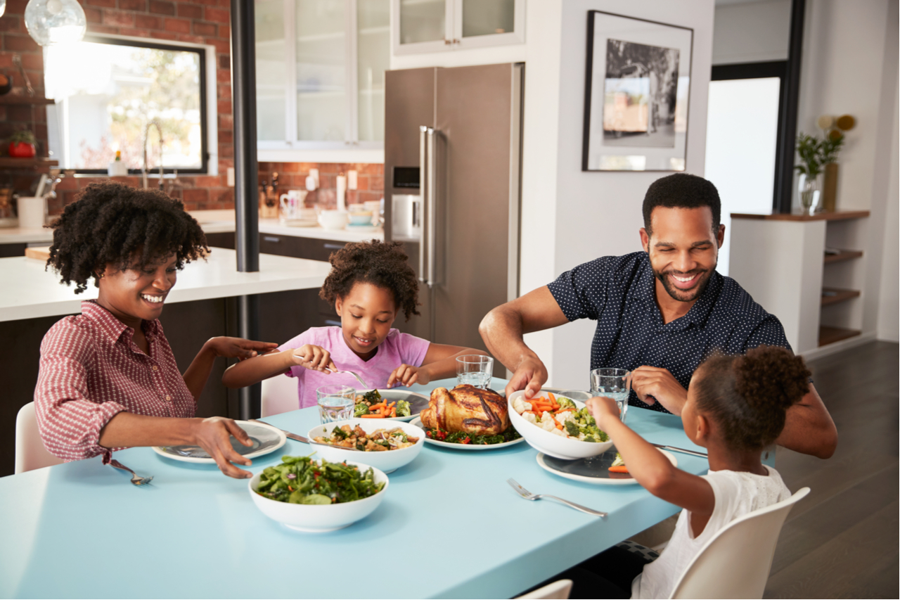 Enjoying family dinner around table at home together.