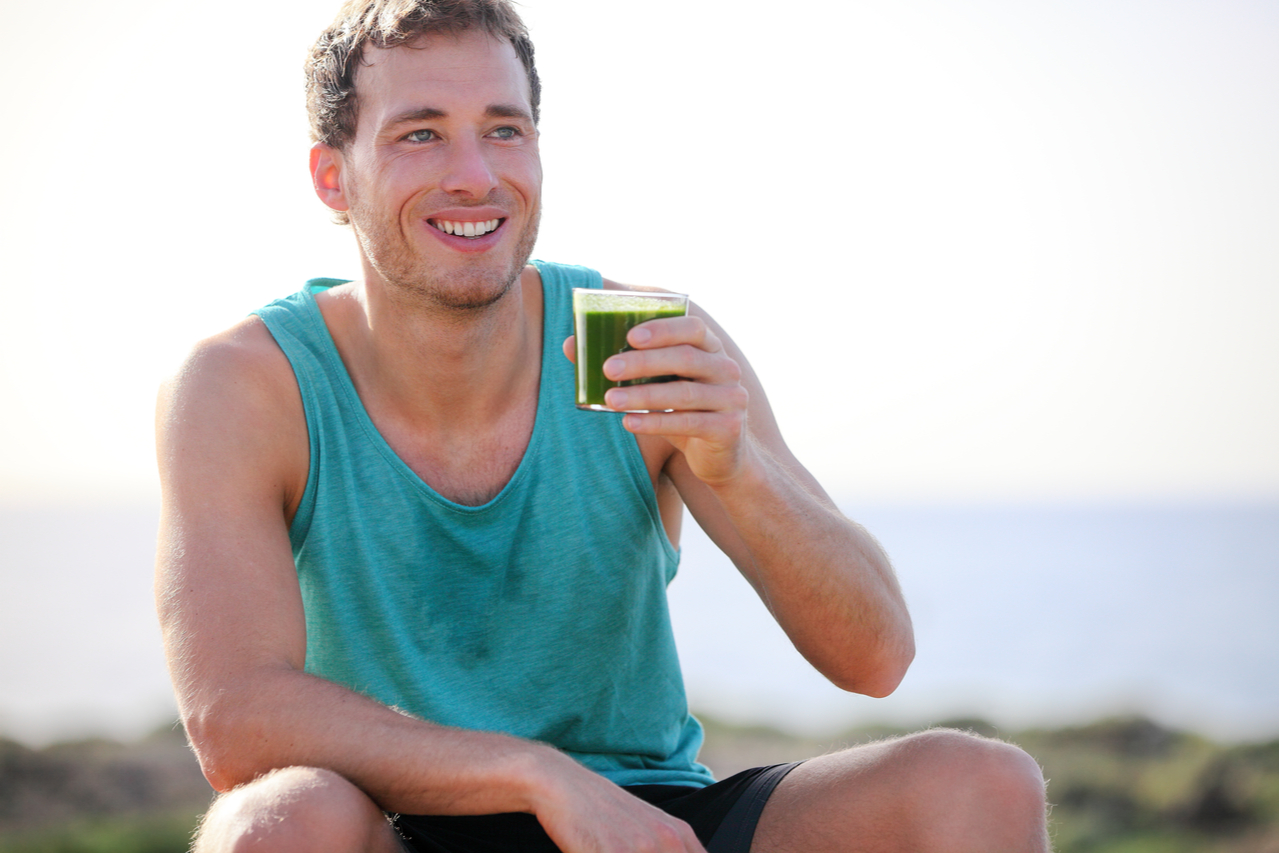 Man drinking ladder superfood greens outdoors before a workout.