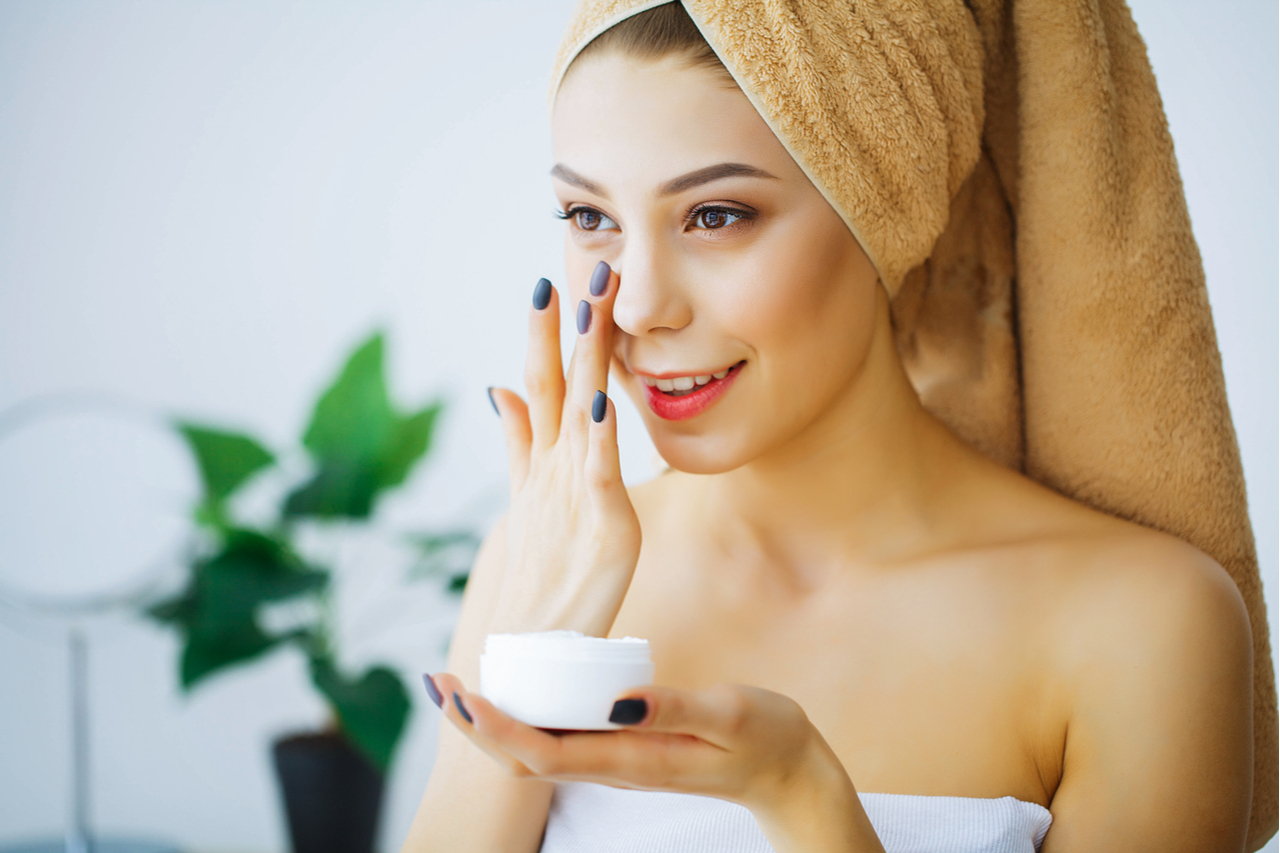 A woman applying sunscreen to her face after taking a bath. 