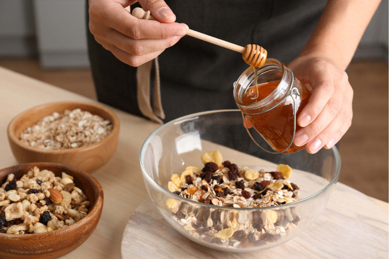 Woman preparing healthy granola bar at wooden table in kitchen.