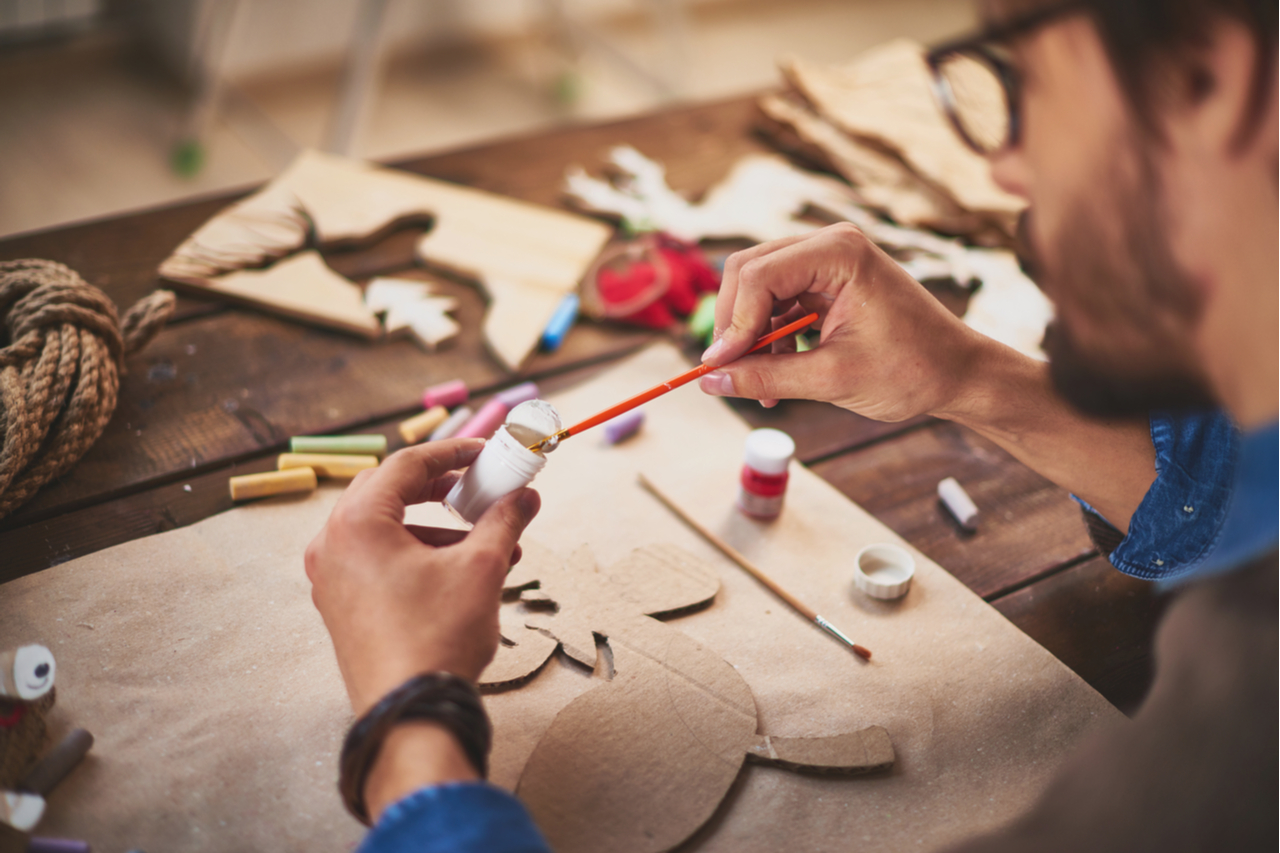 Close-up of craftsman painting xmas symbols with white gouache.