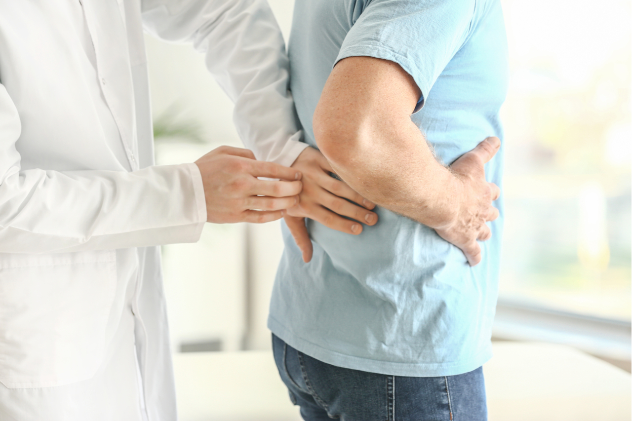 Urologist examining male patient in clinic.