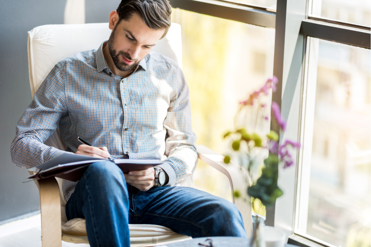 Stylish confident guy writing with journal prompts.