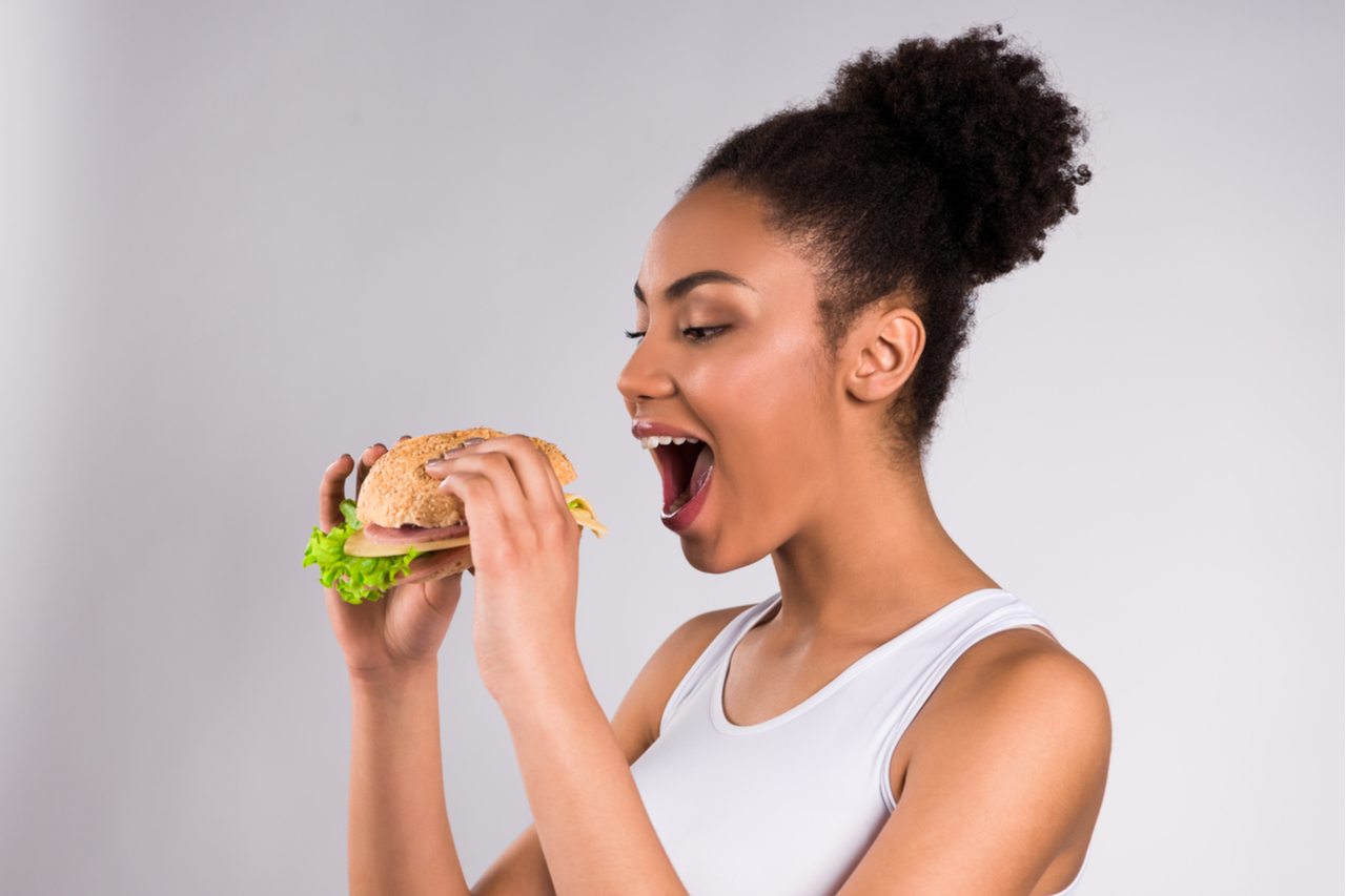 Woman eating hamburger isolated on white background.