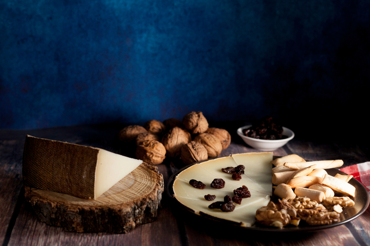 Cheese, raisins and nuts on dish on wood table.