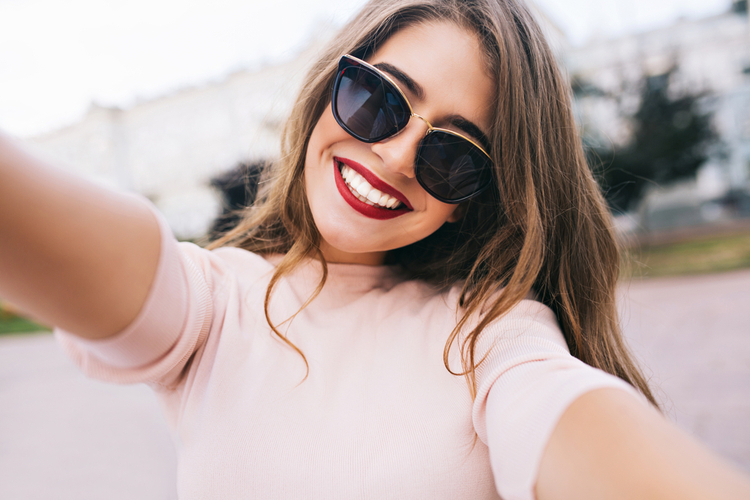 Woman smiling confidently with long hair with sunglasses.