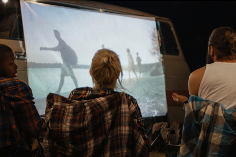 Family having fun and relaxing while watching movie on screen on van in night time as part of things to do for father's day.