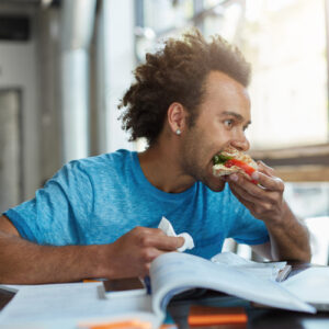 Male student eating while studying.