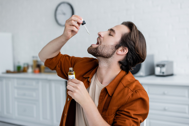 Side view of man taking cbd oil at home.