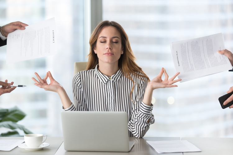 Calm female meditating at work and avoiding multi tasking.