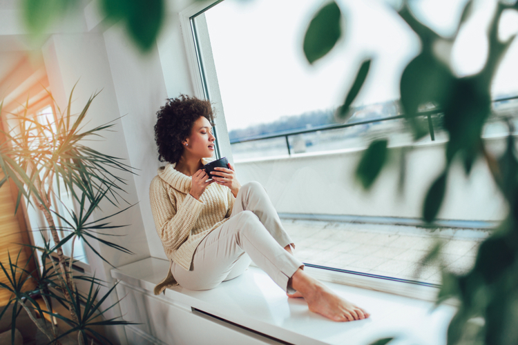 African American woman in her living room drinking holding a coffee mug