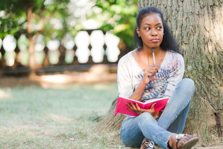 Woman sitting under tree with the best planner journal.