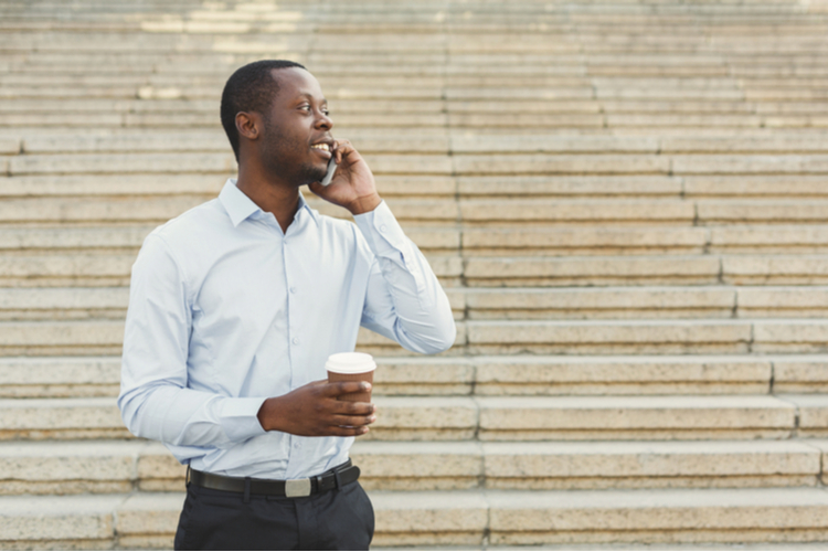 Businessman talking on smartphone and drinking take away coffee outdoors