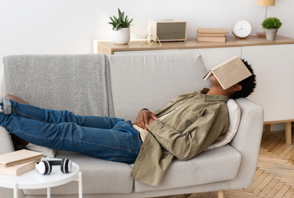 Person laying on the couch, napping, with a book over their face