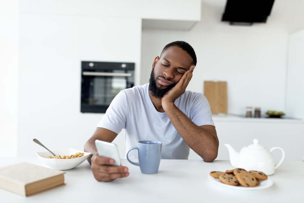 sleepy black man using smartphone