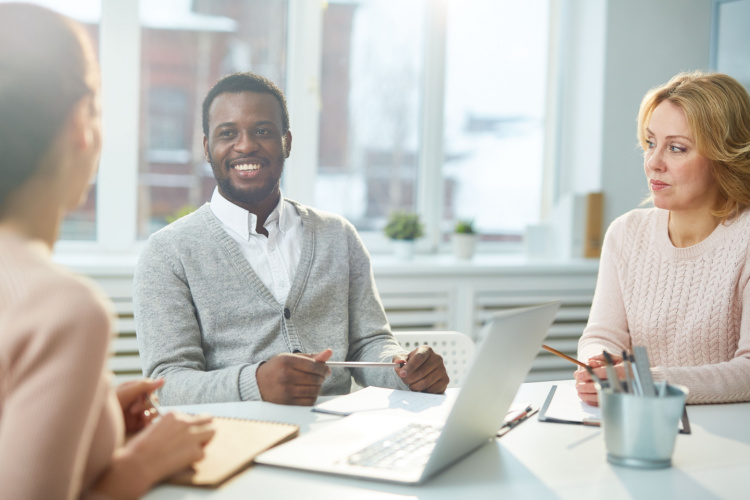 colleagues listening to young woman during discussion of business plan