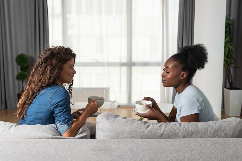 Two friends sitting on the couch listening to each other talk