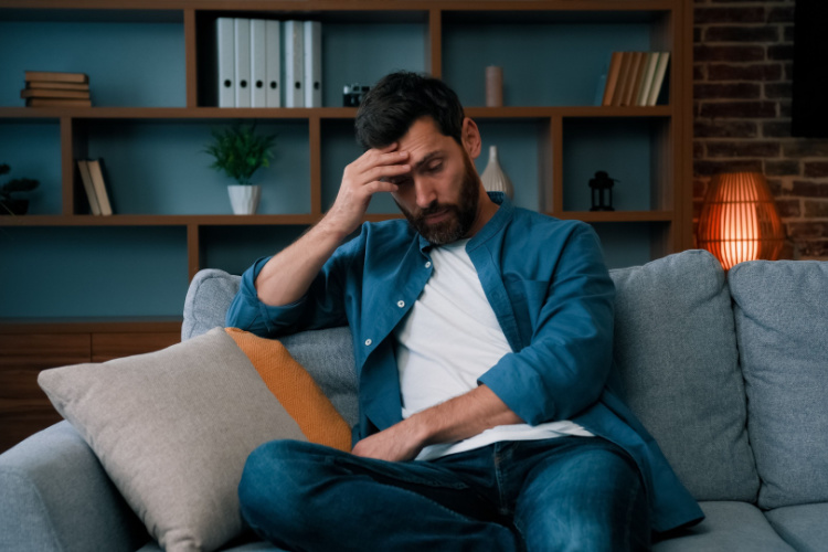 man sit on sofa frustrated about hard working day